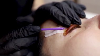 Efendi, silikon banttaki lamine kirpikleri düzeltir ve onları ezer.