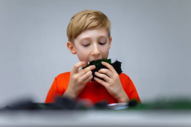 Çocuk plastik bir inşaat setiyle oynuyor. Parçaları dişlerinin yardımıyla ayırıyor.