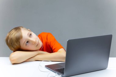 Çocuk masanın üstünde bilgisayarın yanında yatarken çevrimiçi bir ders var.