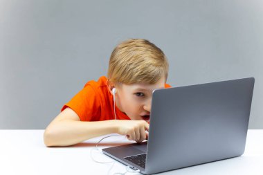 Çocuk dizüstü bilgisayara doğru eğildi ve özenle üzerine yazdı.