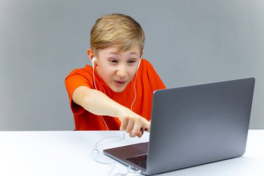 Şaşırmış çocuk parmağını bilgisayara doğrultuyor.