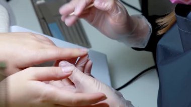 Manikür ustası odun sopayla tırnak etlerini temizler.