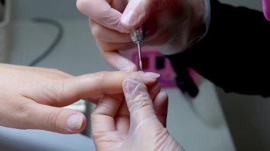 Manikürcü elinde tuttuğu daktilonun yardımıyla tırnak etlerini düşürür.