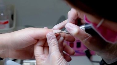 Manikürcü elinde tuttuğu daktilonun yardımıyla tırnak etlerini düşürür.