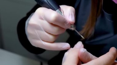 Manikür işlemi bir makinenin yardımıyla, usta müşterinin çivisi üzerinde çalışır.