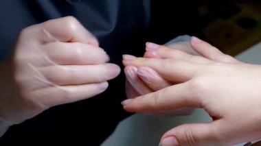 Manikür ustası peçeteyle çiviyi siliyor.