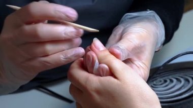 Manikür prosedürü. Usta, çivinin altındaki toprak kalıntılarını tahta bir sopayla değiştiriyor.