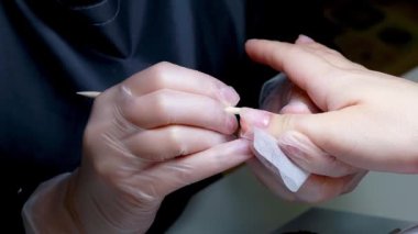 Manikür ustası peçeteyle çiviyi siliyor.