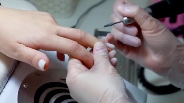Manikür ustası müşterinin tırnaklarındaki jöle cilasını özel bir boron makinesiyle çıkarıyor.