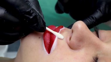 Kalıcı makyaj prosedüründen önce, dudaklardaki kırmızı lekeleri pamuklu bezle sil.