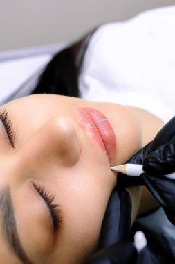 Dudakların kalıcı makyajından önce modelin dudaklarına işaretler uygulanıyor.