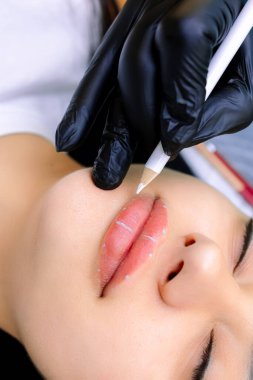 Modelin dudaklarındaki işaretler kalıcı makyaj işlemi için beyaz bir kalemle yapılır..