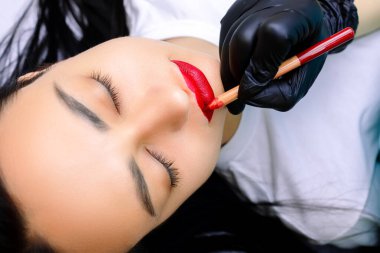 Usta, dudak modellerini yüksek kalite dövme için kırmızı kalemle boyuyor.