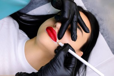 Kalıcı makyaj prosedüründen önce beyaz kalemle dış hatları belirleyen modelin dudaklarının yakın plan görüntüsü