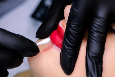 Üstat, pigmenti vurgulamak ve silmek için parmaklarıyla modelin dudaklarını uzatır ve dudaklarının kontürünü vurgular.