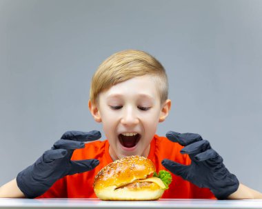 Masada çizburgeri olan bir çocuk ağzını açtı ve elleriyle almak istedi.