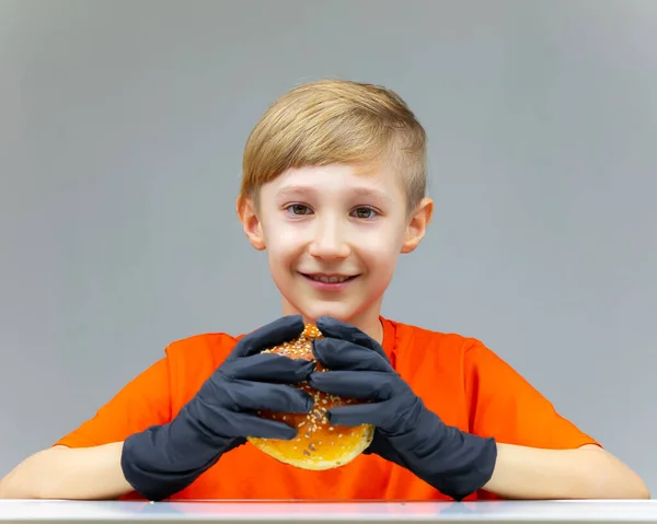 Neşeli Gülümseyen Çocuk Masada Oturur Önünde Sulu Bir Hamburger Tutar — Stok fotoğraf