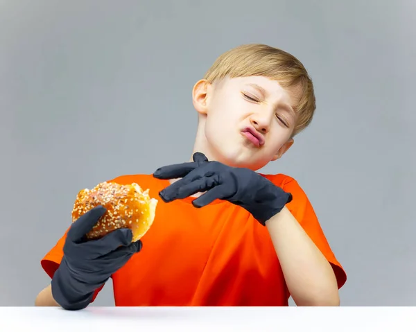 男孩拿着一个被咬的汉堡包 把它推开 表示他不喜欢它的味道 — 图库照片
