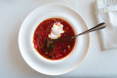 Ekşi kremayla tatlandırılmış bir restoranda kar beyazı bir masa örtüsü üzerinde Ukrayna Borsch 'u.