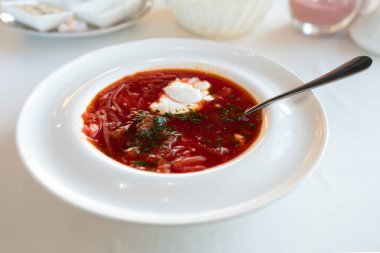 Ekşi kremayla tatlandırılmış bir restoranda kar beyazı bir masa örtüsü üzerinde Ukrayna Borsch 'u.