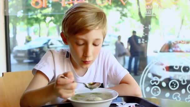 一个坐在咖啡店大窗户前的男孩坐在桌旁 吃着汤 — 图库视频影像
