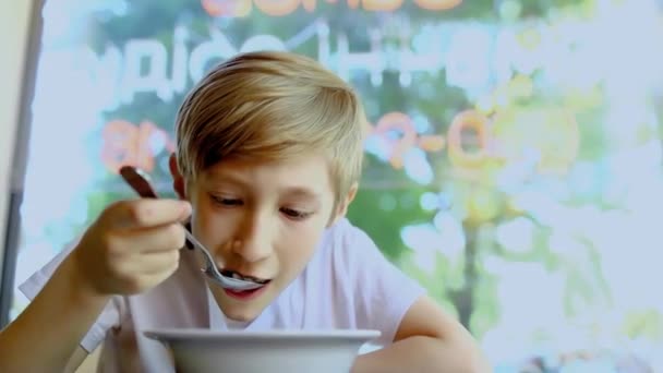 餐馆里的一个男孩趴在一盘鸡汤上 一边吃一边朝窗外看 — 图库视频影像