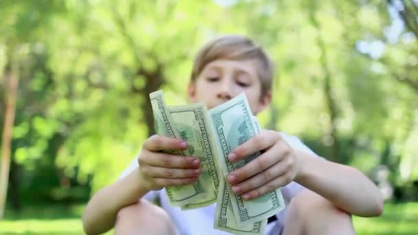 男孩拿着的钱包的特写 他坐在公园里 拿着美元钞票 兴高采烈 — 图库视频影像