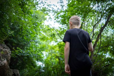 Oğlan ormanda seyahat ediyor.