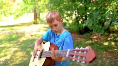 a boy with a guitar tunes the strings of a guitar