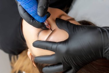 Üstat kaşlarının dövmesini yaptırır ve modelin kaşlarına kalıcı makyaj uygular.