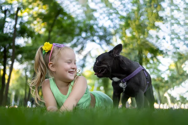 Cheerful Little Girl Lies Lawn Park Looks French Bulldog Who — Foto de Stock