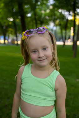 little girl model posing in the park in a green suit