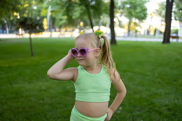 Little Model Girl Green Tracksuit Posing Park Front Camera Adjusting — стоковое фото