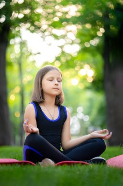 Nilüfer pozisyonundaki parkta meditasyon. Küçük kız meditasyon yapıyor ve rahatlıyor.