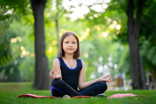 Little Girl Sitting Park Meditates Folded Lotus Position Looks Camera — Fotografia de Stock