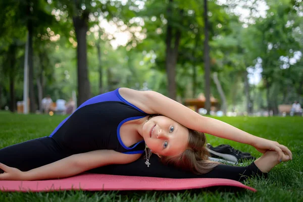 a little girl performs yoga elements leaning to the side stretching her arm and stretching for stretching elements