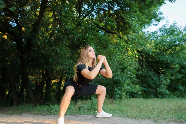 Slender Girl Fitness Model Black Tracksuit Performs Squats Holding Her — 图库照片