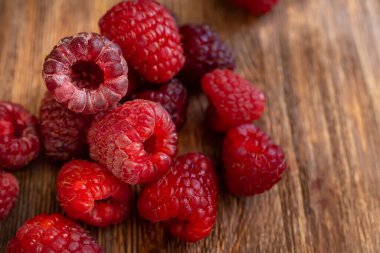 a handful of juicy fresh red raspberries on a wooden table