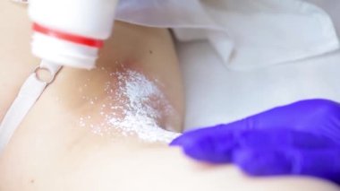 close-up after the electrolysis procedure, the master treats the armpit area with a special powder