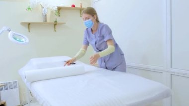 the master of electrolysis and removal of excess hair prepares his workplace clogs the sheet on the couch