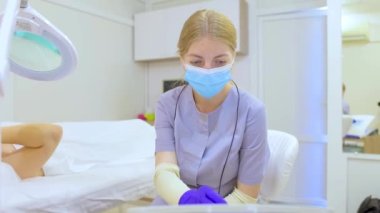 doctor for electrolysis and unwanted hair removal sits in front of the device