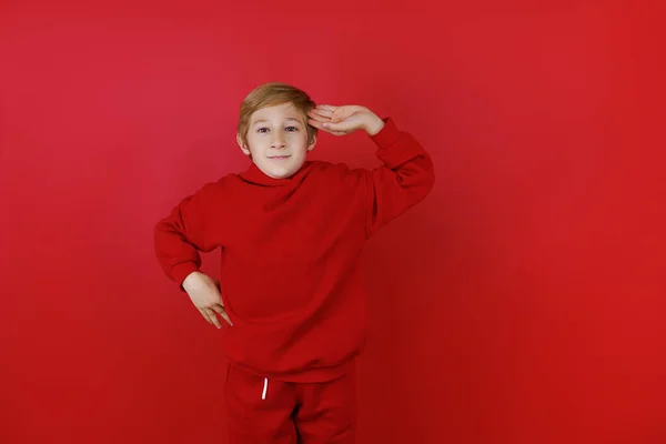 Czerwonym Tle Stoi Chłopiec Ubrany Czerwony Garnitur Który Przyłożył Rękę — Zdjęcie stockowe
