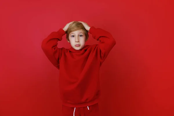Czerwonym Tle Stoi Chłopiec Ubrany Czerwony Garnitur Złapał Się Głowę — Zdjęcie stockowe
