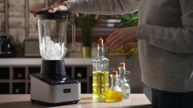 Kadın mutfakta blender 'da buz kırıyor.