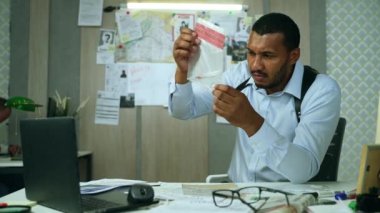 Handsome detective working on evidences of case sitting in his cabinet. Handsome focused cop doing investigation job analyzing some evidences and clues in safe zip packages. High quality 4k footage