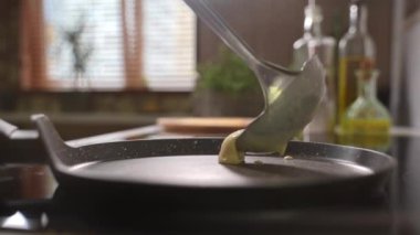 The hand checks if the pan is hot and pours the dough for pancakes. Homemade pancake cooking process in a frying pan in the kitchen. Making for family delicious breakfast meal