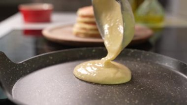 Pancake cooking process in a frying pan. Close up shot of spatula flipping pancake in hot frying pan. Making pancake homemade recipe pancake for family delicious breakfast meal.High quality 4k footage