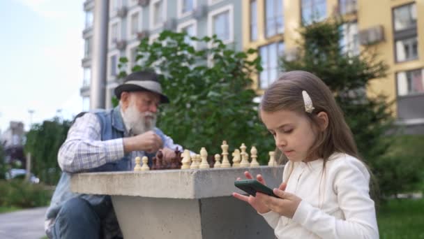 Little Cute Girl Playing Game Smartphone Paying Attention Her Senior — Vídeo de Stock