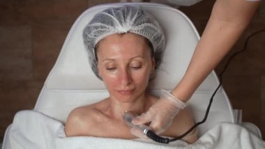 Güzel, 40 'lı yaşlarda orta yaşlı bir kadın kozmetoloji kliniğinde boyun kaldırma ameliyatı oluyor. Cerrahi olmayan kozmetoloji, yaş gençleştirme karşıtı cilt bakımı, güzellik tedavi konsepti. 4K görüntü