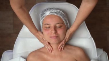 Kozmetik uzmanı kadın müşteriye rahatlatıcı bir boyun masajı yapıyor. Cerrahi olmayan kozmetoloji, profesyonel cilt bakımı, güzellik tedavi konsepti. Yüksek kalite 4K görüntü